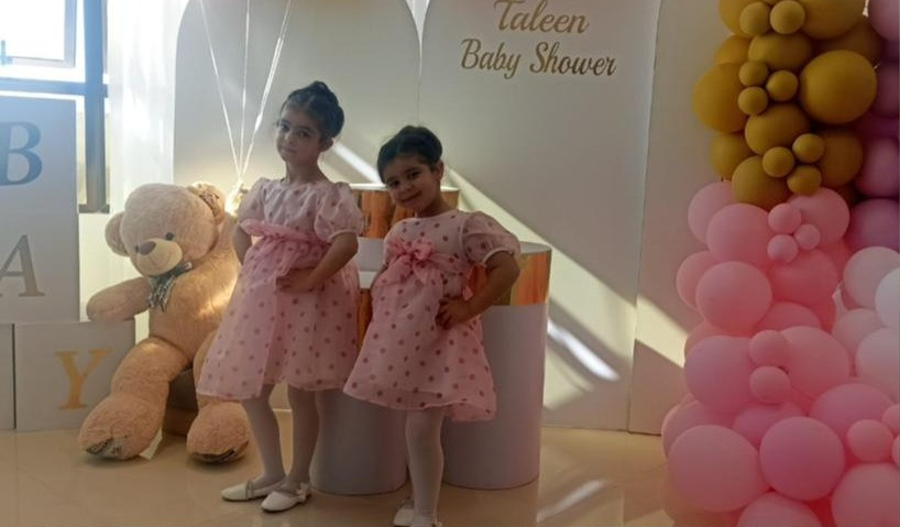 A photo of Mira and Nadia, two little girls in matching pink polka dot dresses.